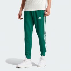 Spodnie dresowe męskie adidas Essentials French Terry Tapered Cuff 3-Stripes. Zielone spodnie dresowe męskie ADIDAS, bez wzorów, z dresówki. Za 184.99 zł.