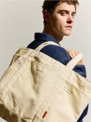 Materiałowa torba na ramię - złamana biel. Torby męskie na ramię Reserved, bez wzorów, z materiału, na ramię, małe. Za 69.99 zł.