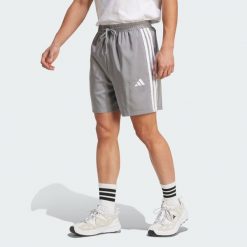 Szorty Essentials 3-Stripes Chelsea. Białe szorty sportowe męskie ADIDAS, bez wzorów, z materiału, sportowe. W wyprzedaży za 89.25 zł.