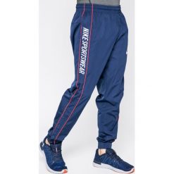 Nike Sportswear - Spodnie. Niebieskie długie spodnie sportowe męskie Nike Sportswear, bez wzorów, z poliesteru. W wyprzedaży za 129.90 zł.