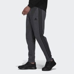 Spodnie męskie adidas Essentials French Terry Tapered Cuff 3-Stripes Pants. Czarne długie spodnie sportowe męskie ADIDAS, bez wzorów, z polaru. Za 179.99 zł.