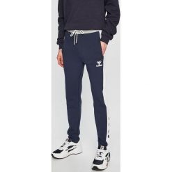 Hummel - Spodnie. Niebieskie długie spodnie sportowe męskie HUMMEL, bez wzorów, z bawełny. W wyprzedaży za 139.90 zł.