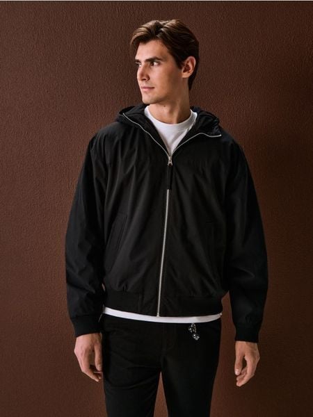 Kurtka bomberka z kapturem - czarny. Czarne kurtki męskie Sinsay, l, bez wzorów, bez ramiączek, z kapturem. Za 119.99 zł.