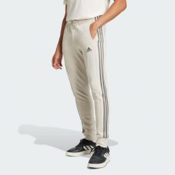 Spodnie Essentials French Terry Tapered Cuff 3-Stripes. Szare spodnie dresowe męskie ADIDAS, bez wzorów, z dresówki. W wyprzedaży za 159.10 zł.