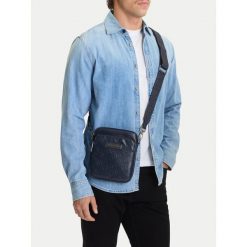 Saszetka Guess Jeans. Niebieskie torby męskie na ramię Guess Jeans, z aplikacjami, z jeansu, młodzieżowe, małe. Za 169.99 zł.